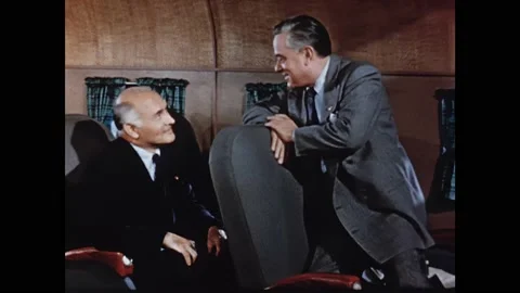 1950s: Men lean over seats and talk on plane. Woman lays mat in play pen. Woman Stock Footage 165426285