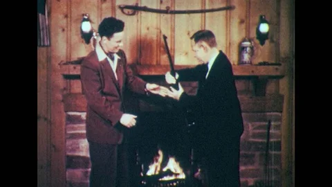 1950s: Men look at rifle by fireplace. Man points gun. Men with gun, man puts Stock Footage