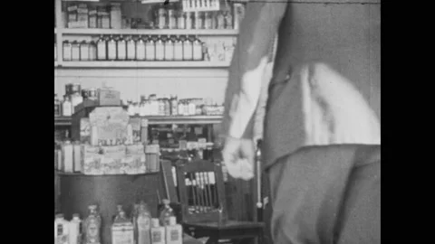 1950s:  Men shake hands and embrace. Man sits, then stands and embraces man. Stock Footage 134353796