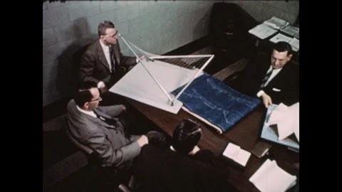 1950s: Men sit at table with blueprints and scale models. Men discuss paperwork Video stock 81838629
