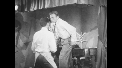 1950s: Men stand up from instruments, man points gun at them. Man gets up from Stock Footage 88665570