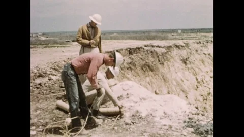 1950s: Men wire explosives at quarry. Men lower explosive into drilled hole. 스톡 동영상 81839163