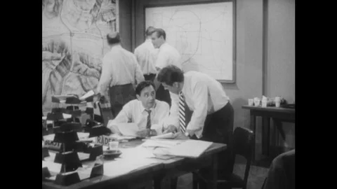 1950s: Men work in emergency response office. Man brings update information to Stock Footage