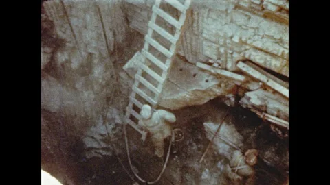 1950s: Men work in pit.  Crane pulls out load of rocks.  Men pour concrete.  Men Stock Footage 88746399