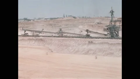1950s: Mining cranes and chutes sit on ledge in quarry. Automated shovel crane Stock Footage 219816693