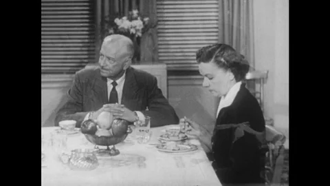 1950s: Parents sit at dinner table. Mother and son do dishes, talk. Mother Stock Footage