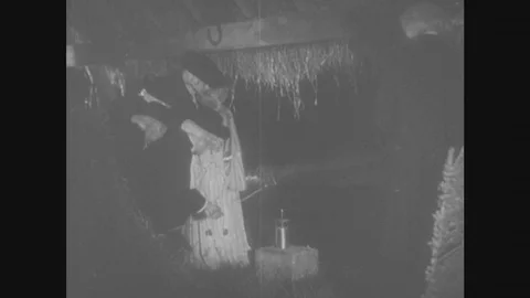 1950S: PEOPLE IN COSTUME HOLD STRING IN BARN. KEY TIED TO STRING NEAR METAL ROD. Stock Footage 80351897