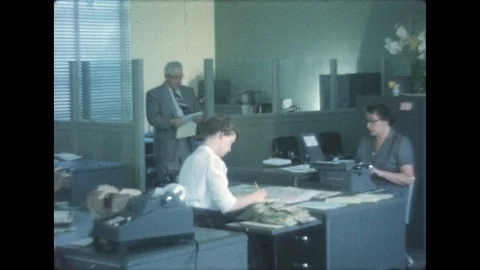1950s: People work in an office. Woman sit at desks, man hands woman paper. Stock Footage