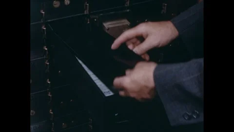 1950s: Person places documents inside safety deposit box in bank. Stock Footage 273882052
