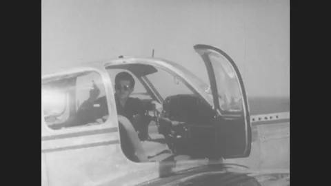 1950s: Pilot sits in cockpit and points up. Airport control tower. Airport Stock Footage 80208951