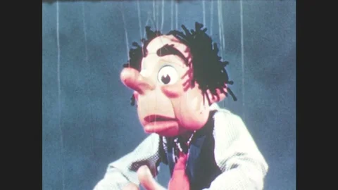 1950s: Puppet holds hands up to head, stands in front of burnt house frame with Stock Footage 79474995