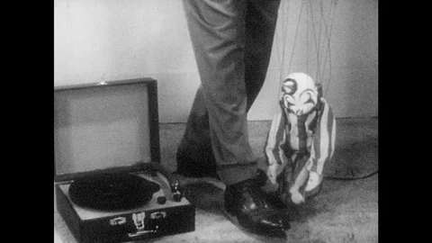 1950s: Puppet sits.  Man turns off record player.  Man opens book of records and Stock Footage 83825328