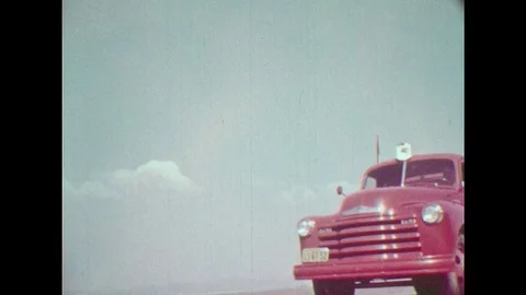 1950s: Red gasoline truck drives. Black train with tank cars. Man with apron Stock Footage