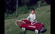 1950S San Francisco: Toddler Boy Next To Red Pedal Car. Women Help Toddler Into Stock Footage