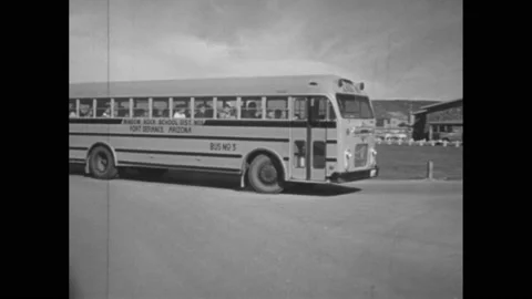1950s: School bus pulls up to school. Students get off bus and enter school. Stock Footage 163225188