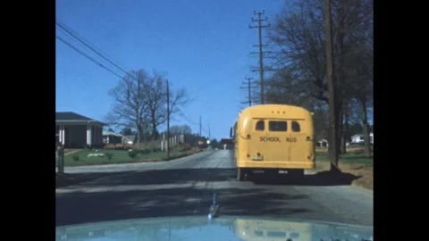1950s: School bus stops in front of car. Car pulls to stop as somebody waves out Stock Footage 272975855
