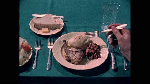 1950s: Slate. Dinner plate with a chop, potato and beans. Hand with fork points Stock Footage 167909403