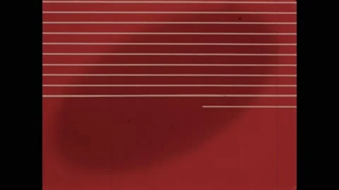 1950s: Spool of fabric cord spirals forward. Lines crisscross on a red field. A Stock Footage 164975675