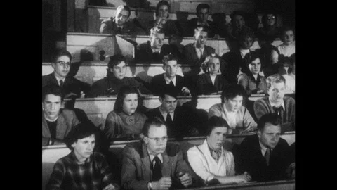 1950s: Students sit in lecture hall. Baby tries to grab toy from hand that moves Stock Footage 83287703