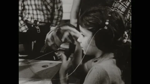 1950s: Switchboard operator plugging in cables. Children playing with a model Stock Footage 164976451