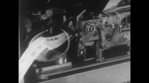 1950s: Tape running through communications machine. Men working on Stock Footage 75112613