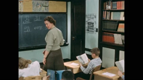 1950s: Teacher instructs students in classroom. Children raise their hands in Video stock 168631266
