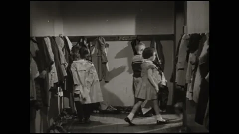 1950s: Teacher stands in empty class watching kids put on coats to leave. Stock Footage 161732894