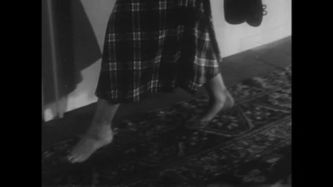 1950s: Tip-toe feet and skirt walk on carpet to door, door closes. Man sits up Stock Footage