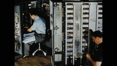 1950s: Tracking shot of men assembling computers. Stock Footage 130357609