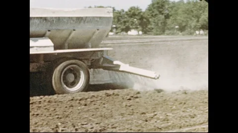 1950s: Truck drives over field on farm, spraying fertilizer on dirt. Combine Stock Footage