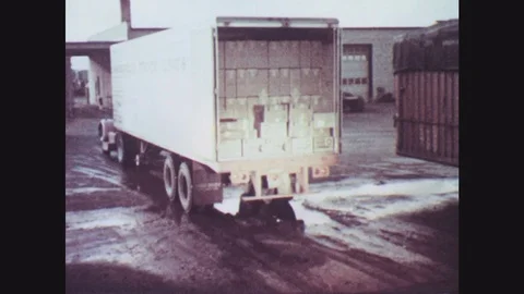 1950s: Truck full of boxes backs up to loading dock. Two men on dock load boxes Vidéo 77424199