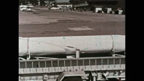 1950s: Truck pulls flatbed trailer with rocket. Trailer and rocket are lifted by 스톡 동영상 234421228
