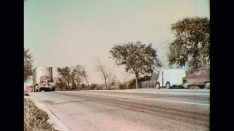 1950s: Trucks pass by each other in the road as meat is delivered into the meat Stock Footage