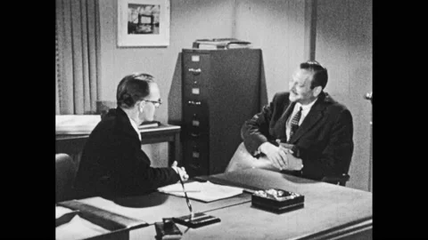 1950s: Two men sit at desk, shake hands, talk. Woman leans over desk, talks to Stock Footage 147400920