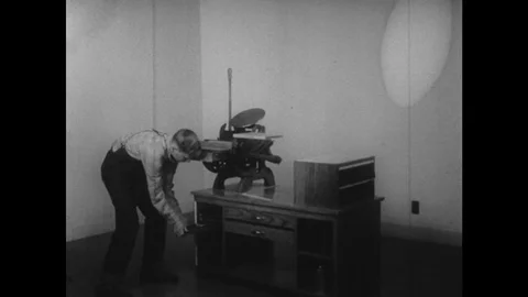 1950s: UNITED STATES: Apprentice prepares book for printing. Boy asks for help. Video stock 75367708