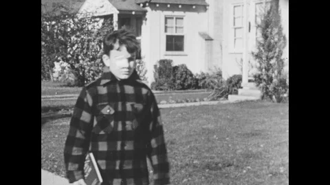 1950s: UNITED STATES: boy with eye patch walks down road. Girl cuts out paper in Stock Footage