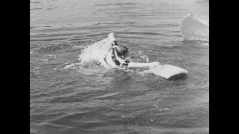 1950s: UNITED STATES: boy in water grabs on to float. Boys play with gun in Stock Footage