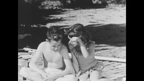 1950s: UNITED STATES: girl and boy talk by pool. Boy dives into pool. Boy jump Stock Footage