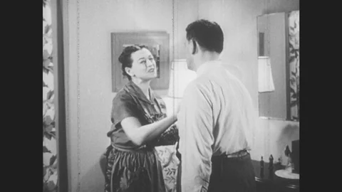 1950s: UNITED STATES: lady talks to man. Man looks in mirror and speaks. Man Stock Footage