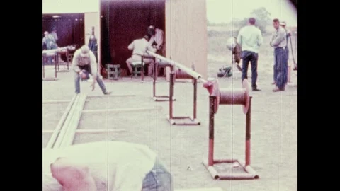 1950s: UNITED STATES: men lift pipes on to rollers on site. Stock Footage 98009850