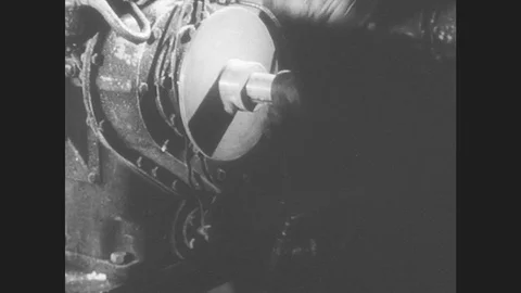 1950s: United States: Men In Protective Suits Turn Handle On Engine During Lab Stock Footage