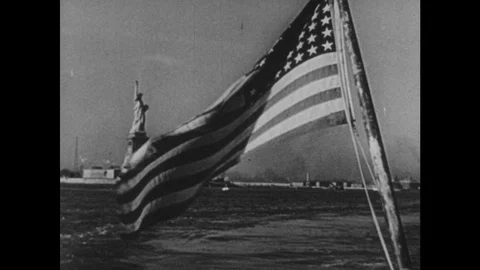 1950s: U.S. Flag waves over water, Statue of Liberty, boat. Aerial view of Video stock 93325860