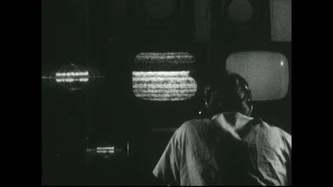 1950s: View from behind, man in TV control room, zoom in on monitors. Stock Footage 74760918