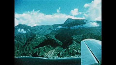 1950s: View from inside airplane of mountains with clouds and shore. A ship Stock Footage 90101032