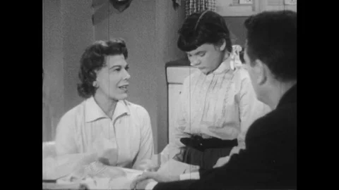 1950s: Woman and man talk to young girl over kitchen table. Girl shakes head, Stock Footage