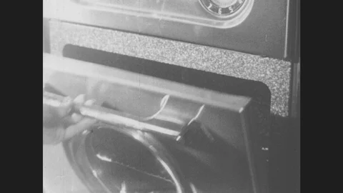 1950s: A woman puts two TV dinner in the oven and turns the dial. She sits and Stock Footage