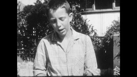1950s: Wooden box full of comic books. Boy gestures in frustration and speaks. Stock Footage 83312870