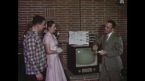 1950s: Young couple talk to man in house. Man shows couple a television. Man Stock Footage