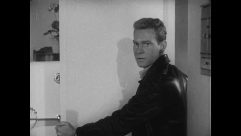 1950s: Young man holds door open, speaks, nods, smiles, leaves through door. Stock Footage