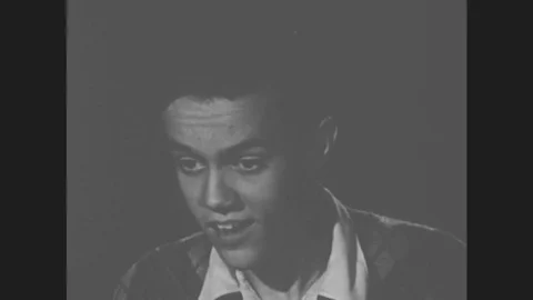 1950s: Young man stands and talks to seated man and standing woman. Stock Footage